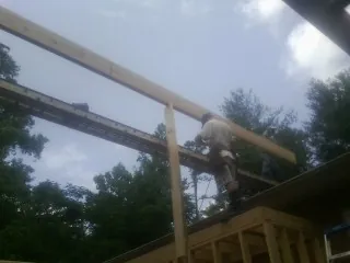 Carpenter setting a ridge beam over a new addition frame — Ice Dam Removal by Roofing Brothers in Miller Place
