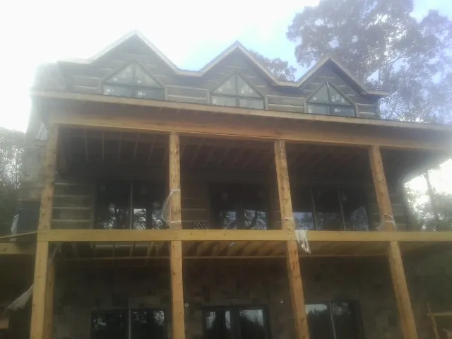 Dormers and porch framing on a large log home under construction — Roof Coating work by our crew in Miller Place