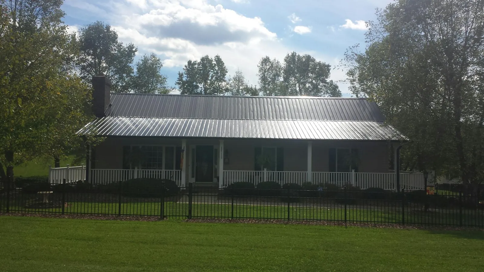 Gray metal roof on a brick ranch with a full width front porch — Gutter Guard Installation work by our crew in Miller Place
