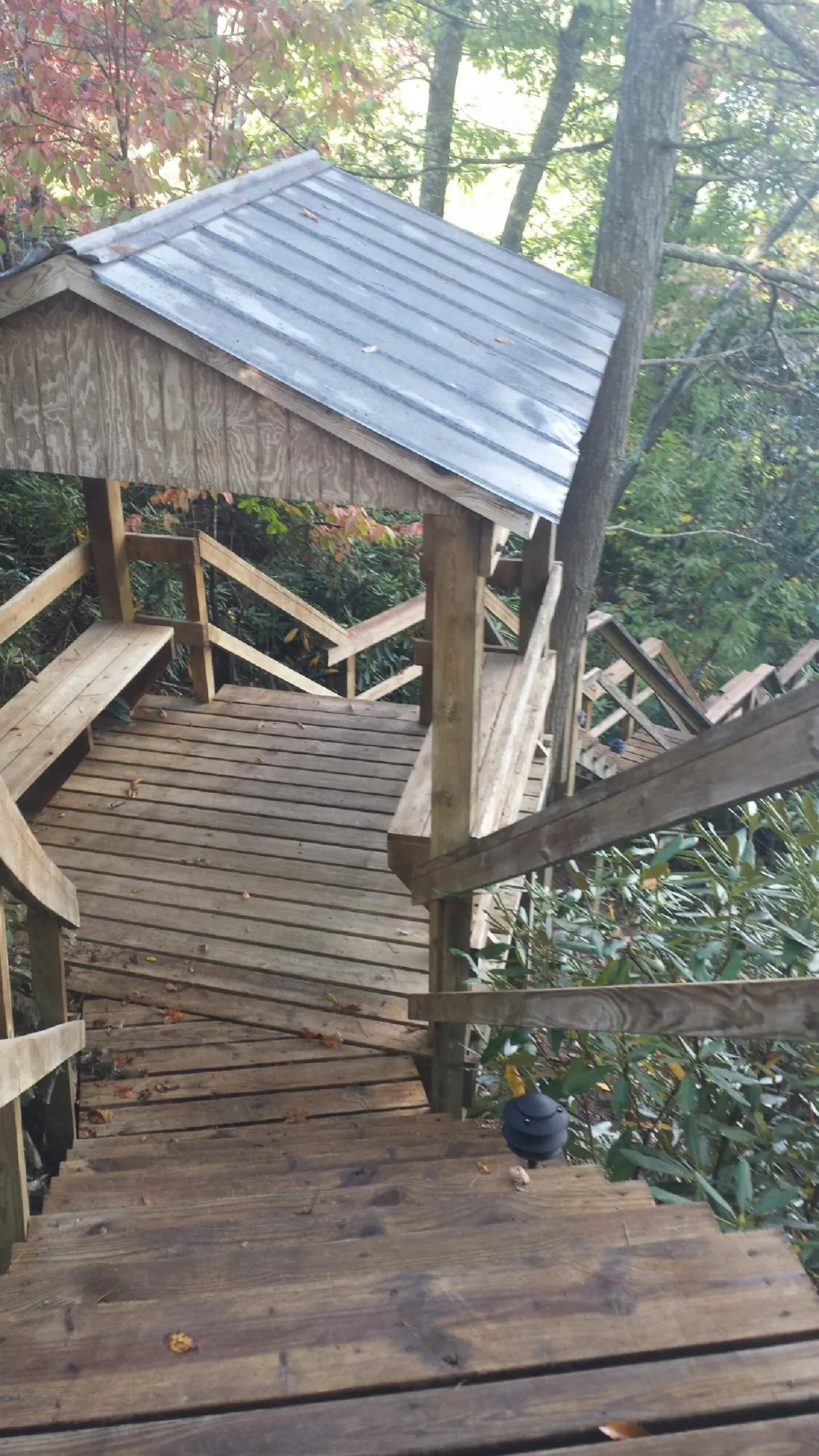 Metal roofed shelter over wooden steps on a wooded walkway — Skylight Repair & Installation work by our crew in Miller Place