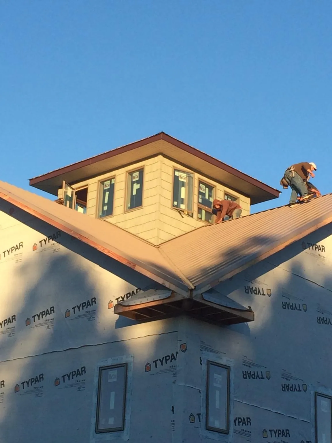 Roofers working around a rooftop cupola on a new metal roof at sunset — Roof Waterproofing in Miller Place by Roofing Brothers